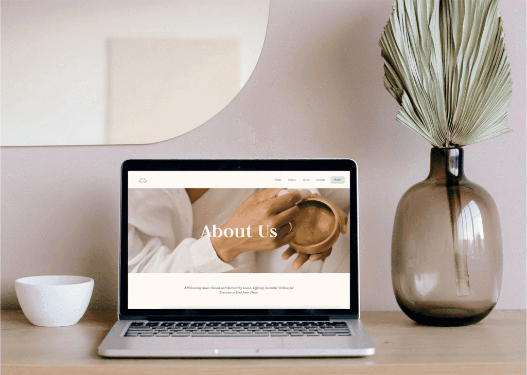 A laptop on a desk with neutral colours, and a concept website of a wellness studio shown on the screen