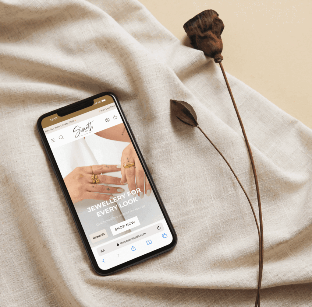 Shopify jewellery website built by Vaughan&Mont for a client, shown on a mobile phone laid down on a neutral linen background